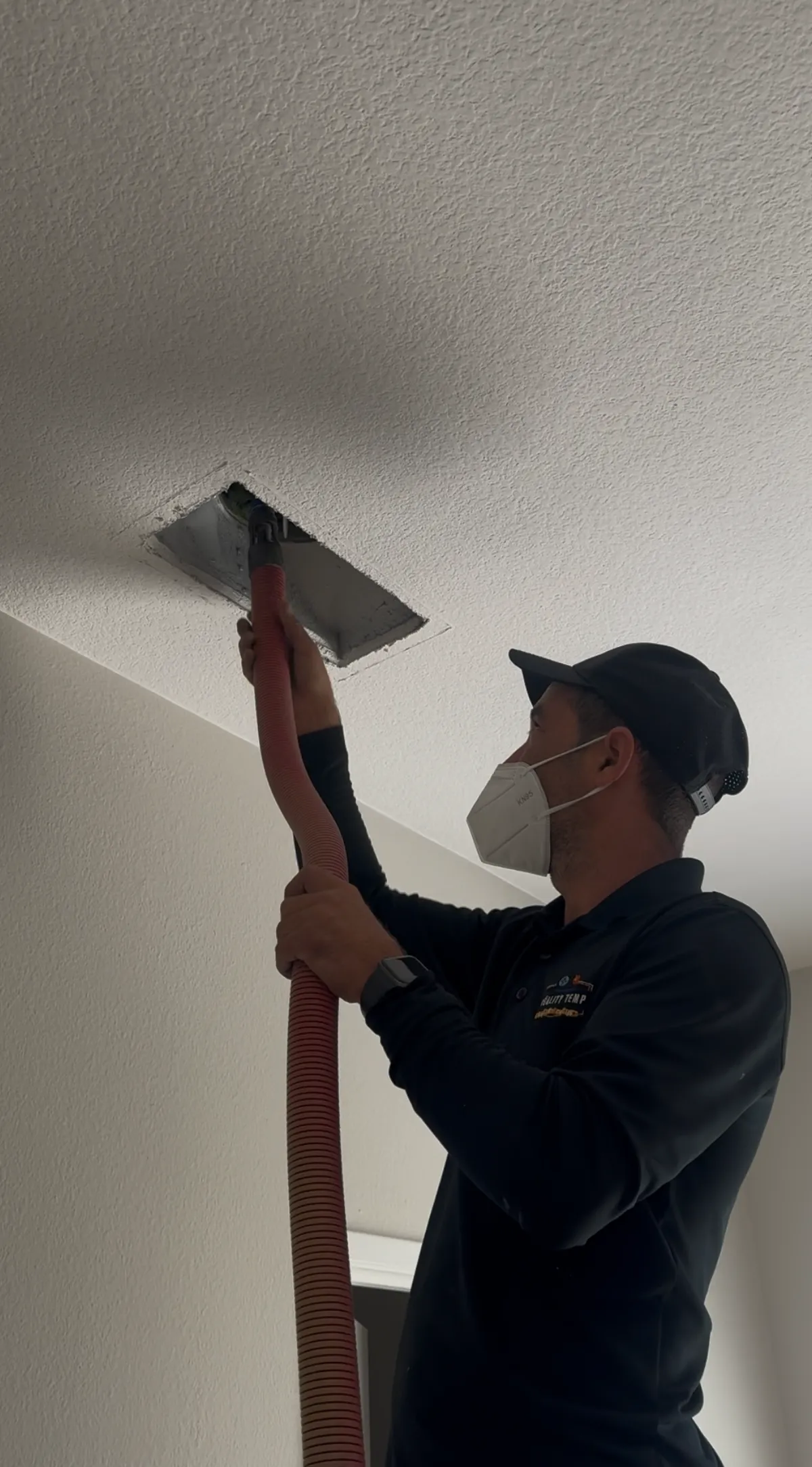 Quality Temp HVAC technician cleaning a ceiling duct register