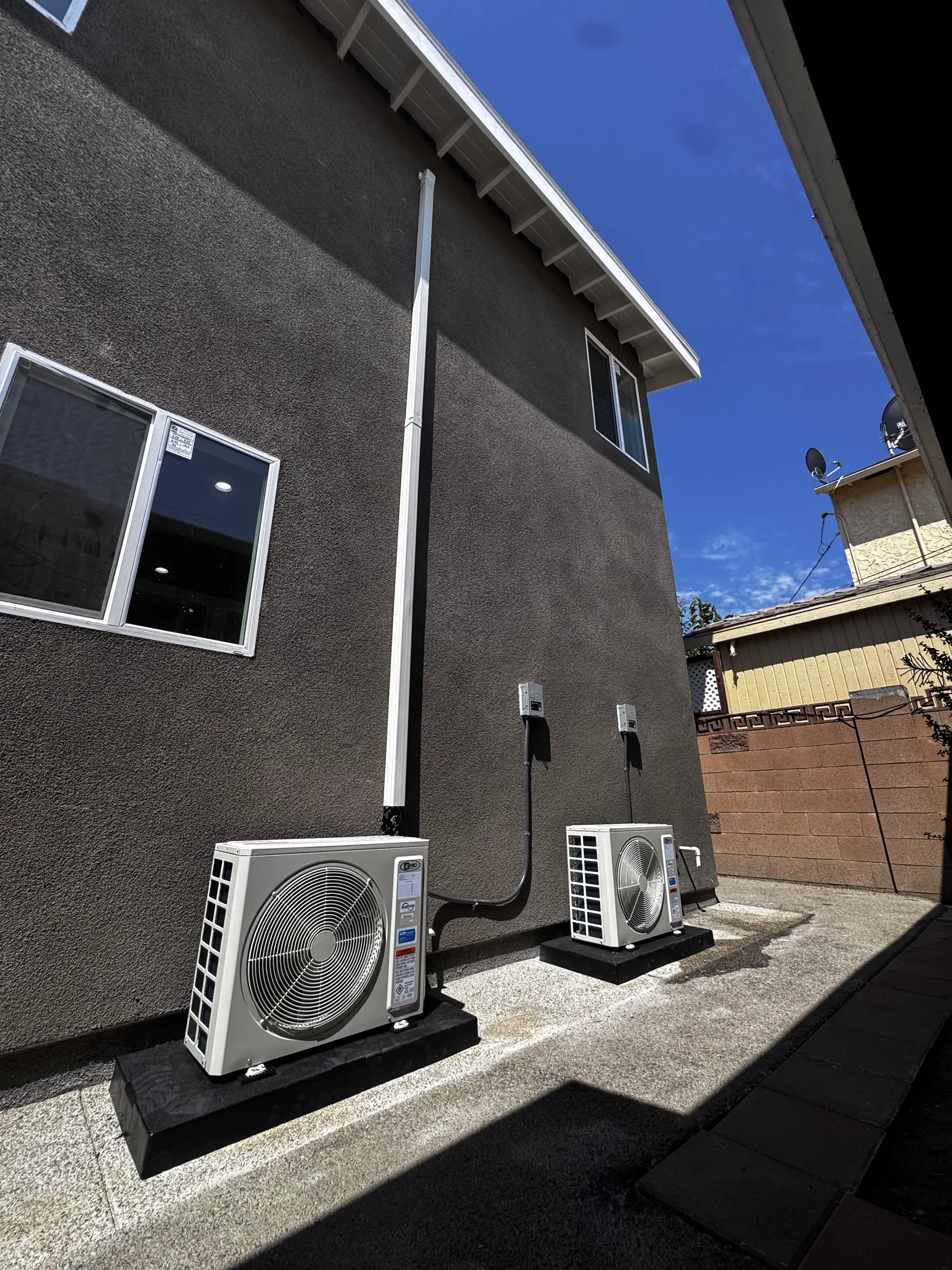 Two outdoor HVAC units beside a home
